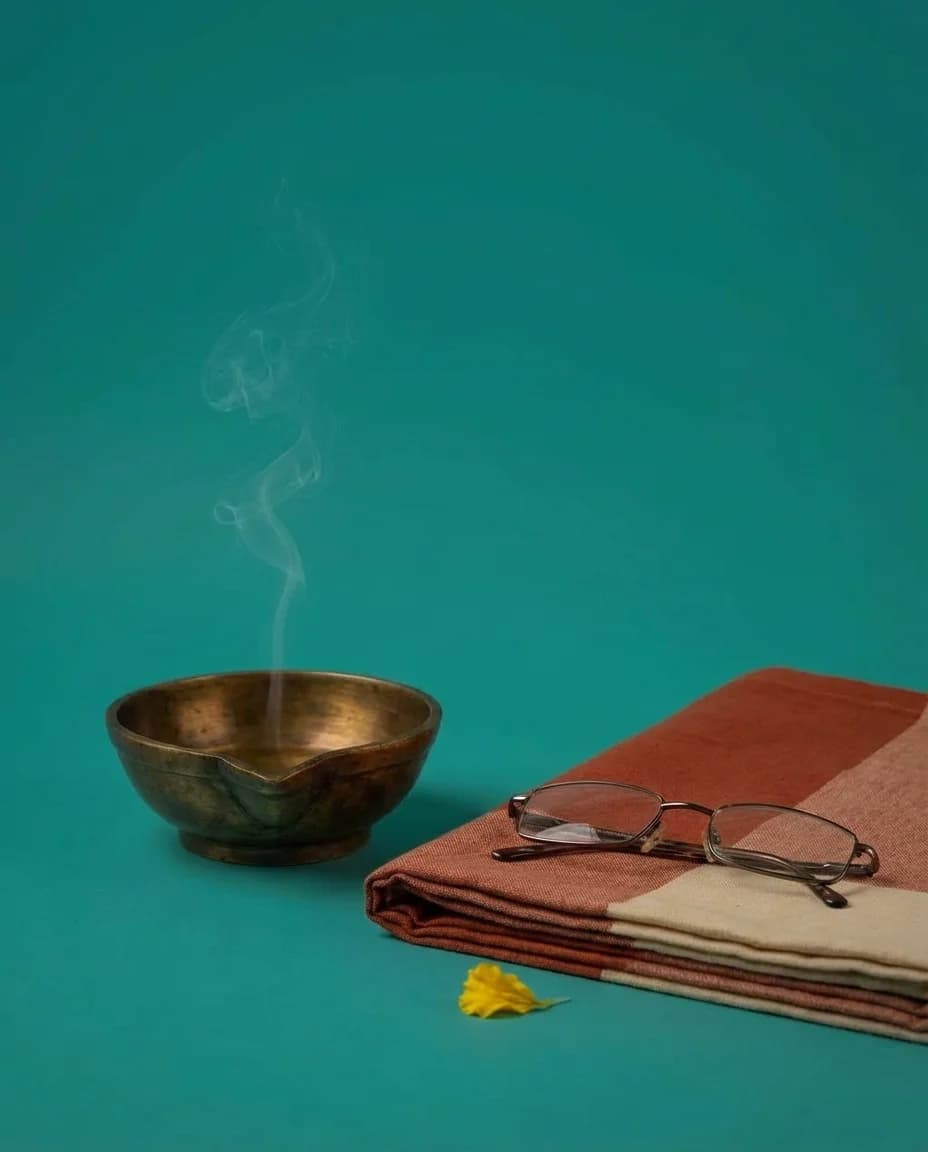 An empty cotton mat with a cold brass diya — the grandmother's absence